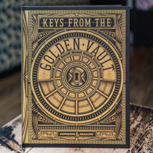 Load image into Gallery viewer, A hardcover book titled 'Keys from the Golden Vault' with ornate gold and black cover art, standing upright on a patterned surface in a real indoor setting.