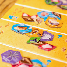 Load image into Gallery viewer, Close-up of a board game with hexagonal cards on a yellow grid