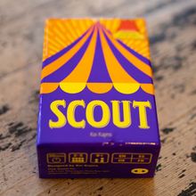 Load image into Gallery viewer, Scout game box with purple and orange design on a wooden surface