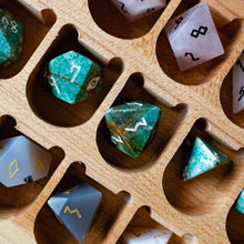 Load image into Gallery viewer, A close-up of a wooden compartment organizer holding assorted polyhedral dice. The dice include green marbled d20s, pale pink d4s, gray d6s with gold numbering, and white d10s with black numbering, arranged in a natural light wood tray.

