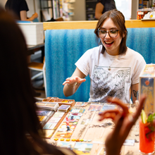 Load image into Gallery viewer, Woman playing a board game with others in a casual setting

