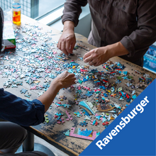 Load image into Gallery viewer, Two people working on a puzzle competition with multicolored puzzle pieces on a table.
