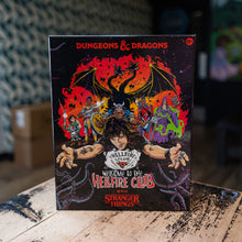 Load image into Gallery viewer, A Dungeons &amp; Dragons box set titled 'Welcome to the Helfire Club' with Stranger Things branding, standing on a rustic wooden table in a dimly lit room.
