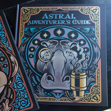 Load image into Gallery viewer, A hardcover book titled "Astral Adventurer's Guide" by Jonathan &amp; Mark O'Sullivan, featuring a whimsical illustration of a hippopotamus wearing a magnifying glass and smoking a cigar, with a dark ornate border and teal, gold, and pink accents.
